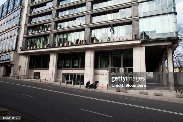 Workmen operate from ropes on the facade of the Warsaw Stock Exchange during exterior cleaning work in Warsaw, Poland, on Thursday, April 11, 2013....