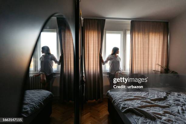 young woman looking out the window after waking up in the morning - overslept stock pictures, royalty-free photos & images