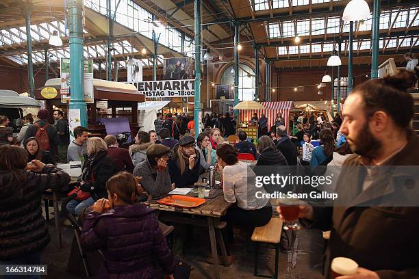 Visitors try out culinary delights from vendors on the first day of Street Food Thursday at the Markthalle Neun market hall in Kreuzberg district on...