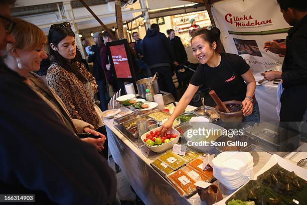 Vendor prepares a papaya salad as visitors look on on the first day of Street Food Thursday at the Markthalle Neun market hall in Kreuzberg district...