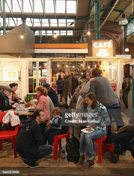 Visitors try out culinary delights from vendors on the first day of Street Food Thursday at the Markthalle Neun market hall in Kreuzberg district on...