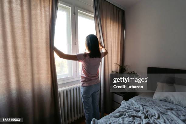 young woman opening up curtains in the bedroom in the morning - overslept stock pictures, royalty-free photos & images