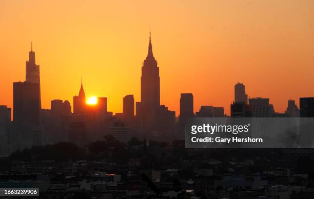 The sun rises behind the skyline of midtown Manhattan and the Empire State Building as a heatwave continues in New York City on September 6 as seen...
