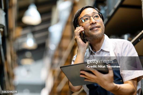 streamlined store operations with online ordering for small business owners. low-angle view of a japanese furniture store owner's discussion with a customer via a smartphone to receive and reconfirm an online order in his store. - personalizzazione foto e immagini stock