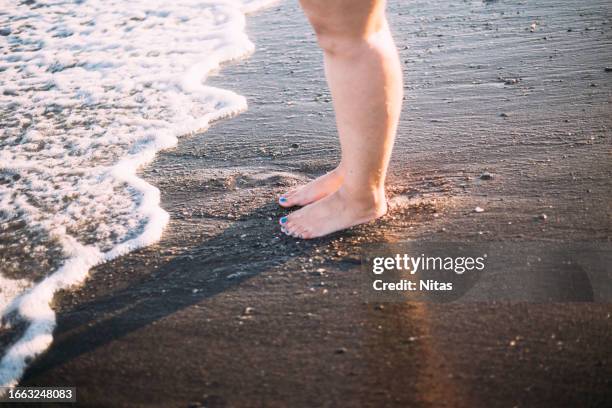 feet of an overweight woman on the seashore - fondale marino foto e immagini stock