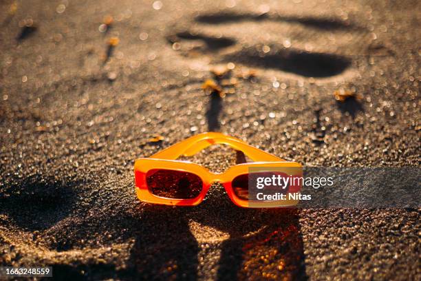 orange sunglasses on the sand of the beach at sunset - festa na praia imagens e fotografias de stock
