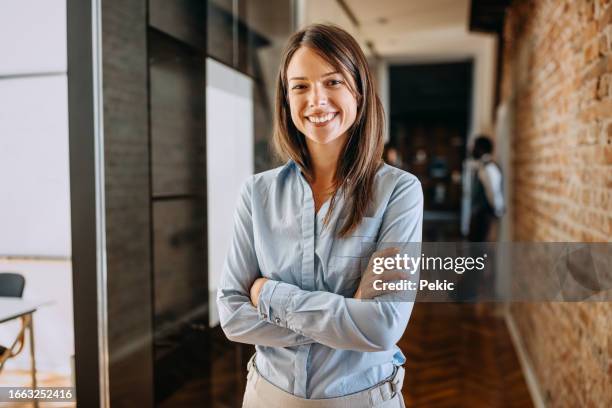 porträt einer fröhlichen, schönen, gut gekleideten geschäftsfrau im modernen büroflur - junge frau allein stock-fotos und bilder