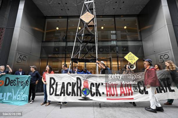Climate activists hold banners, chanting anti-fossil fuel use slogans as they demonstrate in front of the headquarters of Black Rock, one of the...