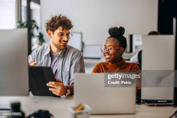 two young colleagues working together at modern office - använda en laptop bildbanksfoton och bilder