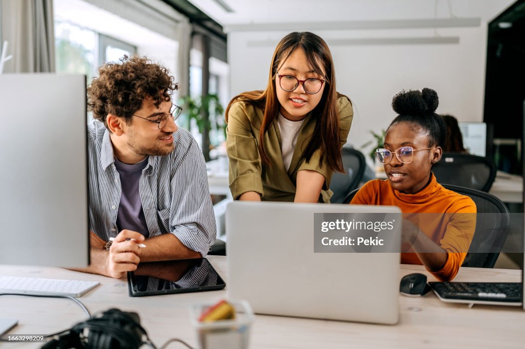 Three young colleagues discussing work at modern office