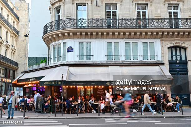 People sit at the terrace of a cafe in the 2nd arrondissement of Paris on September 13, 2023.