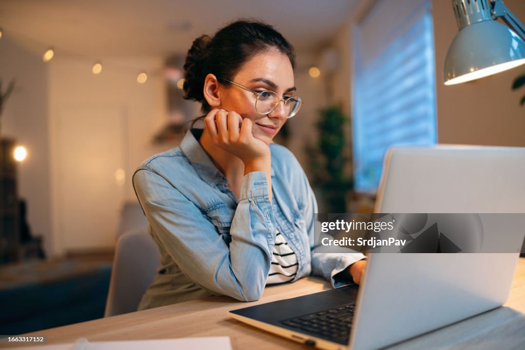 Junge kaukasische Frau, die Laptop benutzt, während sie von zu Hause aus arbeitet
