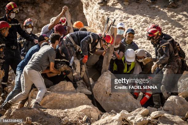 Rescuers use a metal bar and a wooden beam to search for a victim amid the rubble of a destroyed house in the earthquake- hit village of Imi N'Tala...