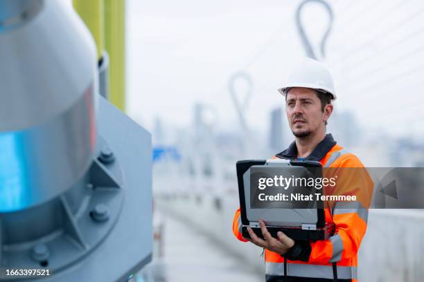 improved planning, building quality, and safe construction with bim technology. a male civil engineer using a laptop to inspect a cable-stayed bridge structure via bim software at a construction site. - bim stock pictures, royalty-free photos & images