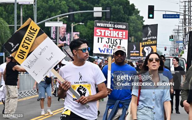 Strikers carry signs as writers and actors staged a solidarity march through Hollywood to Paramount Studios on September 13, 2023 amid a halt in...