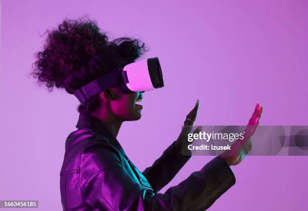 young woman wearing vr glasses in pink neon light - pink coat stock pictures, royalty-free photos & images