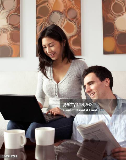 couple relaxing together with newspaper and laptop - baltimore maryland stock-fotos und bilder