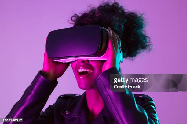 young woman wearing vr glasses in pink neon light - virtual reality headset stock pictures, royalty-free photos & images