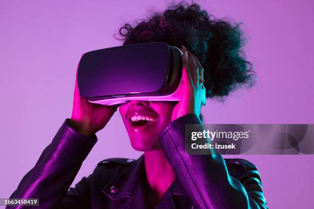 young woman wearing vr glasses in pink neon light - realidade virtual imagens e fotografias de stock