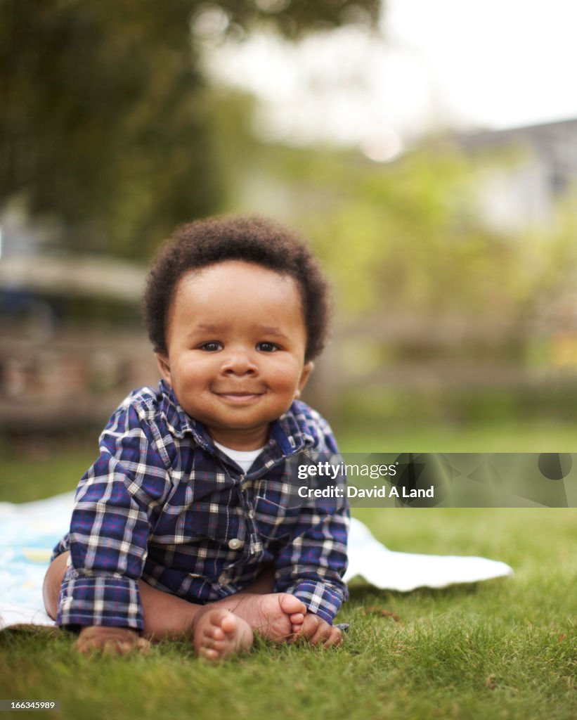 African American baby sitting in grass