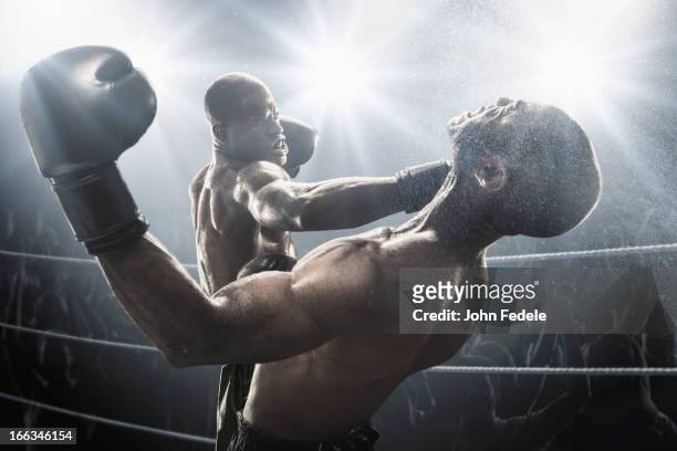 african american boxer hitting opponent in boxing ring - punching stock pictures, royalty-free photos & images