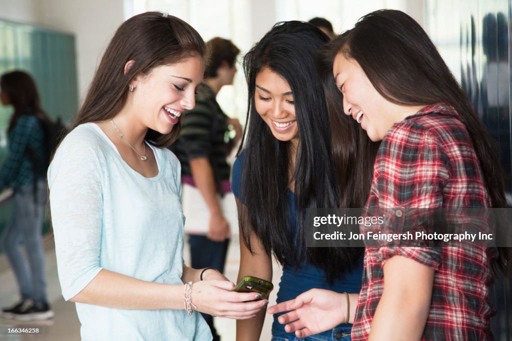 High school students looking at cell phone together