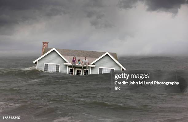 family sitting on roof of house floating in sea - acidente natural imagens e fotografias de stock