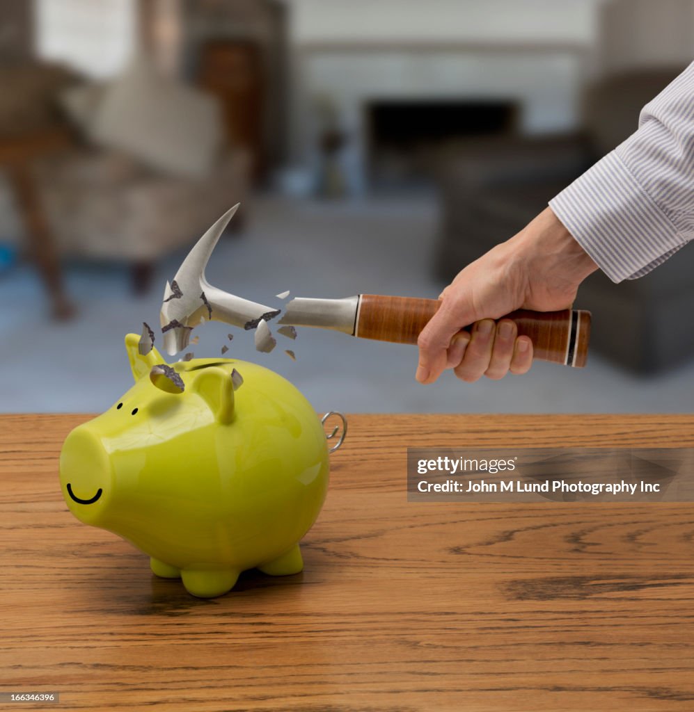 Caucasian man smashing piggy bank