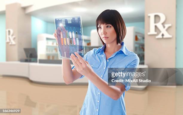 mixed race woman using digital tablet in pharmacy - female pharmacist with a digital tablet imagens e fotografias de stock