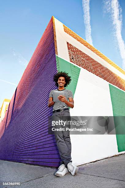 man using digital tablet and leaning on wall outdoors - city from below stockfoto's en -beelden