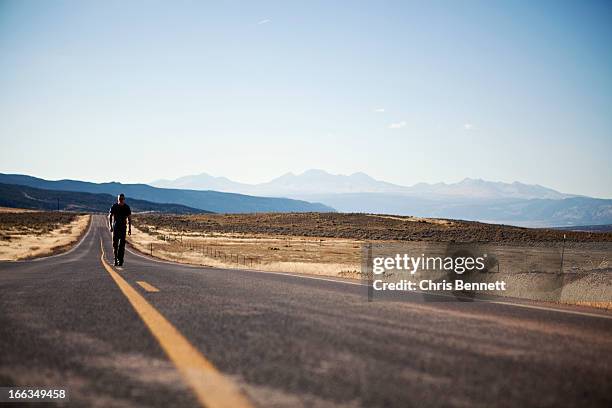 a man walks along a deserted road in western colorado. - naturita stock pictures, royalty-free photos & images