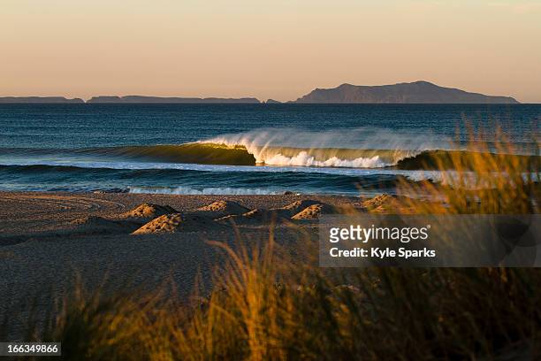 as the sun rises a wave breaks just off the sand in oxnard, california.  the sun is also lighting up anacapa island, which is part of channel islands national park. - oxnard ストックフォトと画像