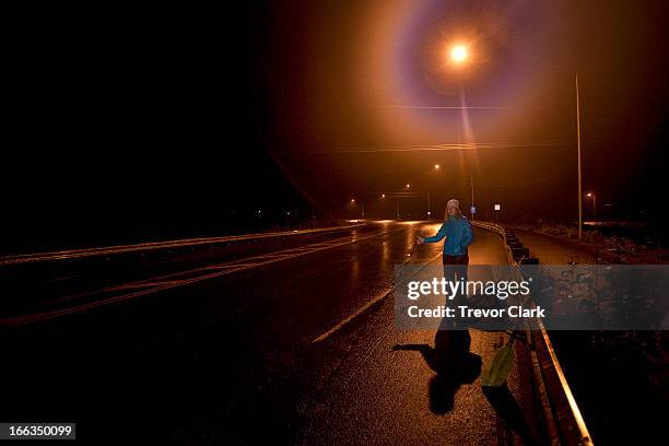 one woman hitch hiking at night under a street light. - hitchhiking 個照片及圖片檔