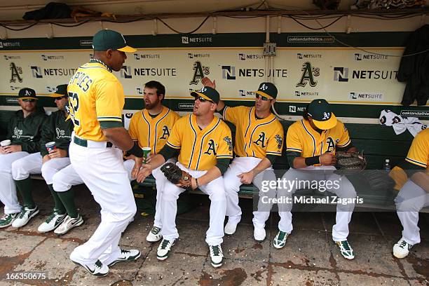 Yoenis Cespedes of the Oakland Athletics gives high fives to Derek Norris, Brandon Moss and Scott Sizemore in the dugout during the game against the...