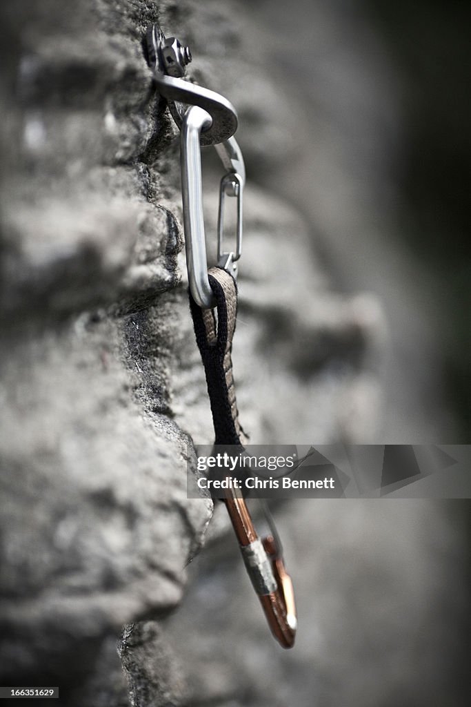Rock climbing equipment hangs from a rock face.