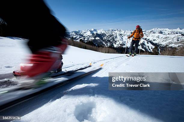 low angle perspective of a skier's boot motion blurred with a skier int he background. - park city utah stock-fotos und bilder