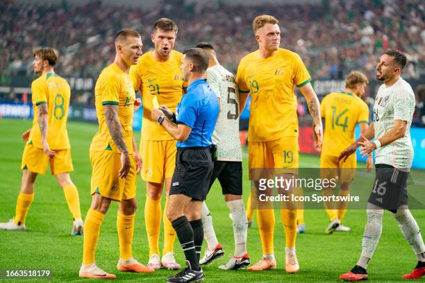Refree Rubiel Vasquez issues a yellow card to Australia forward Mitchell Duke while Australia defender Cameron Burgess and Australia defender Harry...