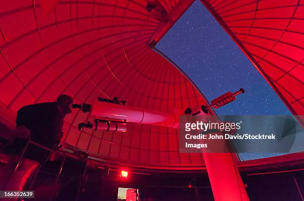 inside the observatory, an astronomer makes observations with a large refractor telescope at the 3rf astronomy campus in texas. - observatory foto e immagini stock