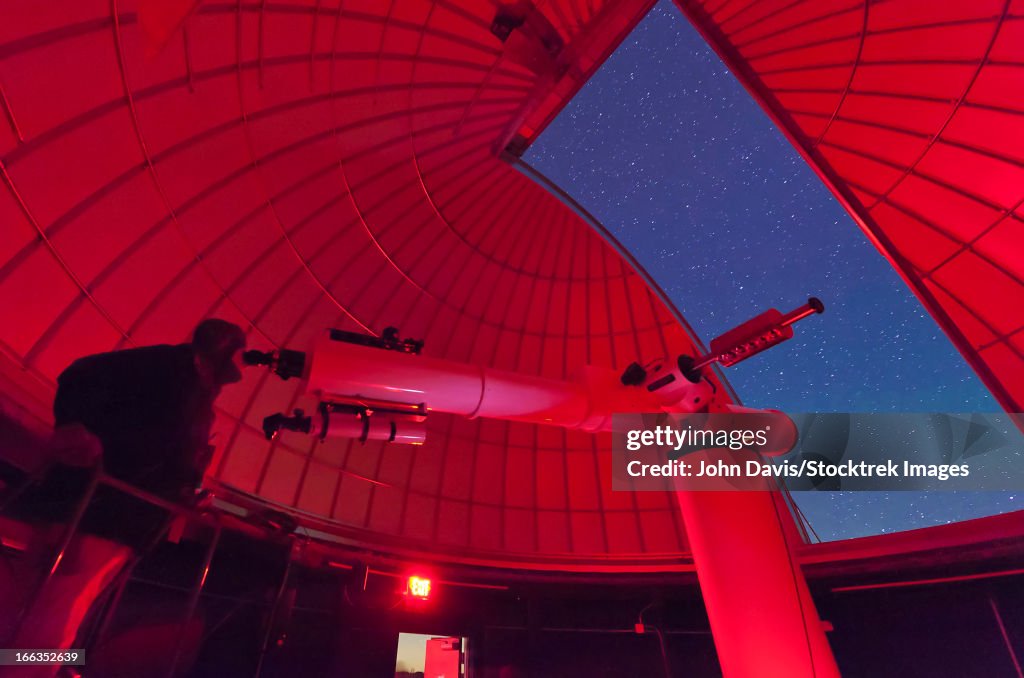 Inside the observatory, an astronomer makes observations with a large refractor telescope at the 3RF astronomy campus in Texas.