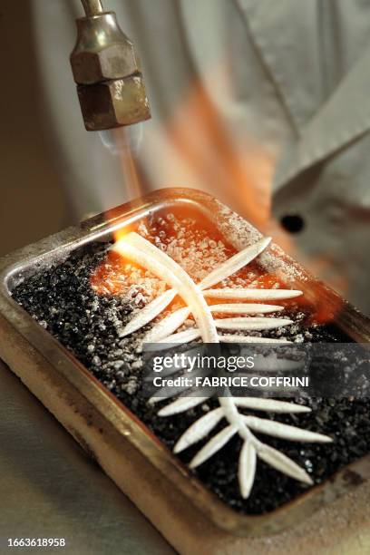 An employee of Swiss Jeweller Chopard uses a blowtorch to heat a Palme d'Or trophy 09 May 2007 at the company's headquarters in Geneva. The...