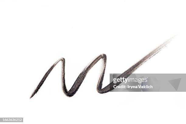 waved black smear of black eyeliner pencil or eyebrow pencil on white background, isolated. cosmetic make-up product for eye and eyelashes. - eyebrow pencil stock pictures, royalty-free photos & images