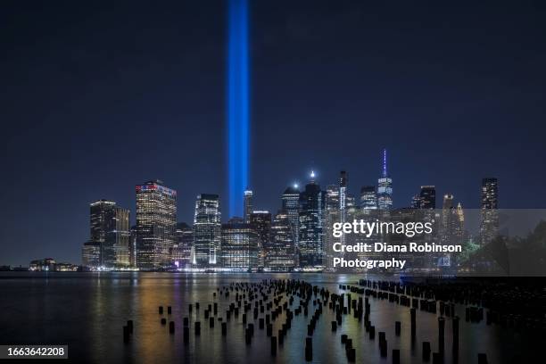 view of the "tribute in light" as seen pilings along the east river and lower manhattan brooklyn bridge park at night - tribute in light stock-fotos und bilder