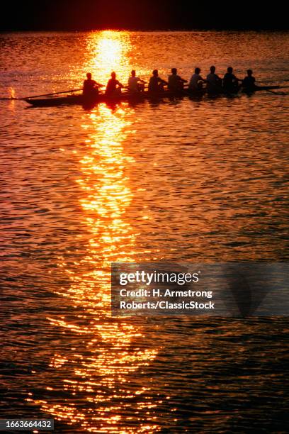 1980s 8 men rowers and a coxswain in a shell an eight rowing sculling on the schuylkill river at sunset philadelphia pa USA.
