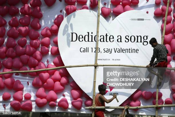 Indian workers fix a Valentine campaign billboard commissioned by Indian mobile phone operater Hutchison in Kolkata, 12 February 2007. Vodafone, the...