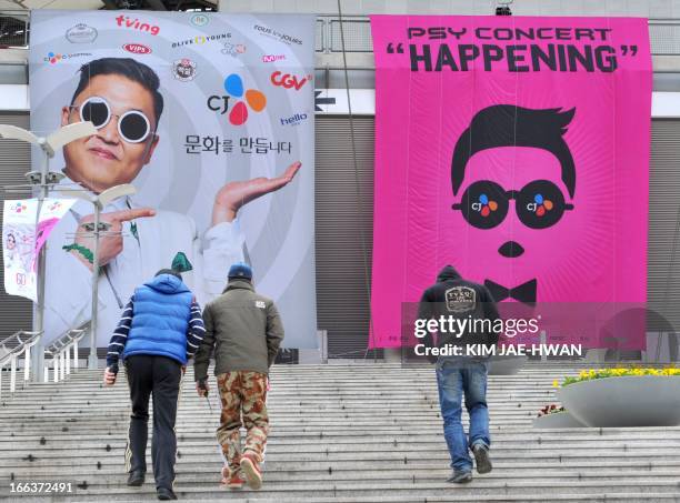 Pedestrians walk past banners advertising a concert by South Korean rapper Psy displayed outside the World Cup Stadium in Seoul on April 12 a day...