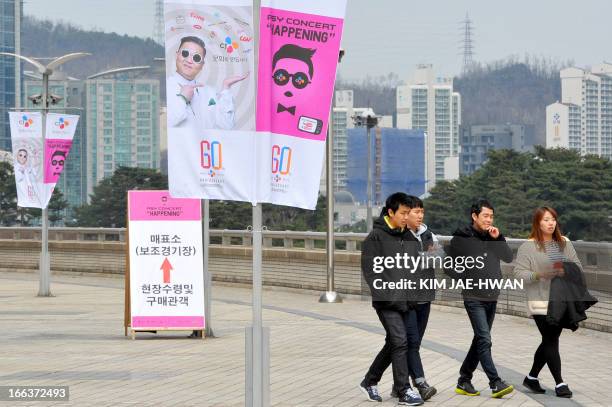 Pedestrians walk past banners advertising a concert by South Korean rapper Psy displayed outside the World Cup Stadium in Seoul on April 12 a day...