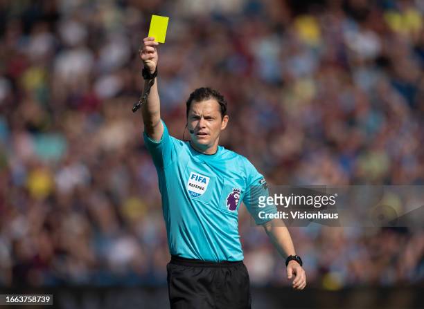 Referee Darren England hands out a yellow card during the Premier League match between Burnley FC and Tottenham Hotspur at Turf Moor on September 2,...