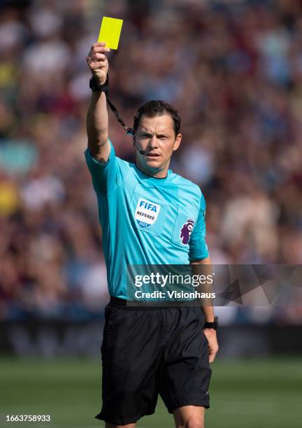 Referee Darren England hands out a yellow card during the Premier League match between Burnley FC and Tottenham Hotspur at Turf Moor on September 2,...