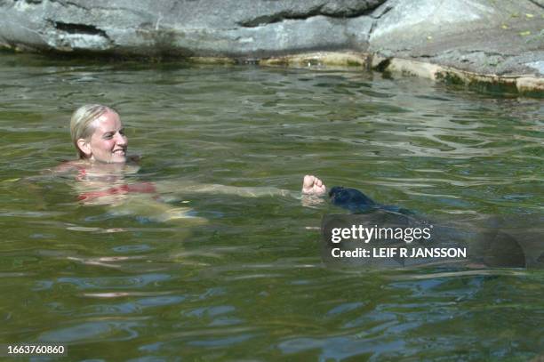 Zookeeper Linda Askelund takes a swim with a young harbor seal in a pond at Stockholm's Skansen Zoo, 26 July 2006. Europe baked again 26 July under a...