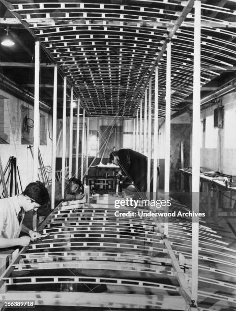 Workers at the de Havilland Aircraft plant construct a replica of the biplane in which Orville and Wilbur Wright made their historic flight at Kitty...